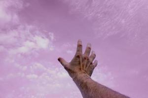 mano arriba gesticulando en el rosado cielo, sentimientos y emociones foto