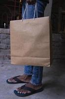 Man holding a liner brown paper bag in his hand. Close up photo