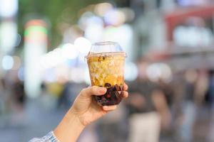 woman hand holding brown sugar boba milk tea with tapioca pearls at night market, famous Taiwanese bubble tea of Taiwan. Street Food and travel in Ximending, Taipei concept photo