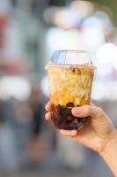 woman hand holding brown sugar boba milk tea with tapioca pearls at night market, famous Taiwanese bubble tea of Taiwan. Street Food and travel in Ximending, Taipei concept photo