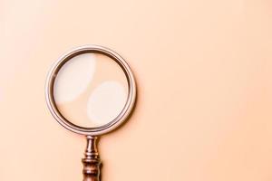 Magnifying glass on orange background. Top view. Flat lay. Copy space. Minimal creative concept. Blue background in pastel colours photo