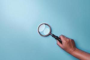 Magnifying glass on blue background. Top view. Flat lay. Copy space. Minimal creative concept. Blue background in pastel colours photo