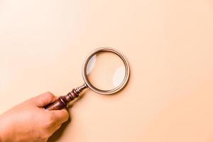 Magnifying glass on orange background. Top view. Flat lay. Copy space. Minimal creative concept. Blue background in pastel colours photo