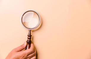 Magnifying glass on orange background. Top view. Flat lay. Copy space. Minimal creative concept. Blue background in pastel colours photo