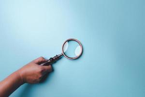Magnifying glass on blue background. Top view. Flat lay. Copy space. Minimal creative concept. Blue background in pastel colours photo