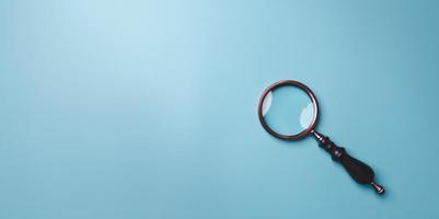 Magnifying glass on blue background. Top view. Flat lay. Copy space. Minimal creative concept. Blue background in pastel colours photo