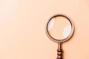 Magnifying glass on orange background. Top view. Flat lay. Copy space. Minimal creative concept. Blue background in pastel colours photo