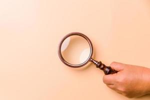 Magnifying glass on orange background. Top view. Flat lay. Copy space. Minimal creative concept. Blue background in pastel colours photo