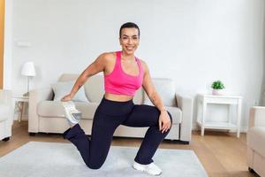 Warming Up Before Workout. Smiling Sporty Black Woman Training At Home Or Fitness Club Studio, Beautiful Female Stretching Legs After Exercises On Mat photo