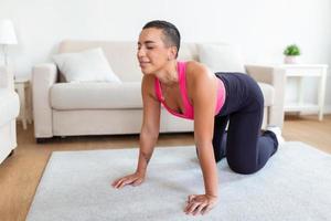 Warming Up Before Workout. Smiling Sporty Black Woman Training At Home Or Fitness Club Studio, Beautiful Female Stretching Legs After Exercises On Mat photo