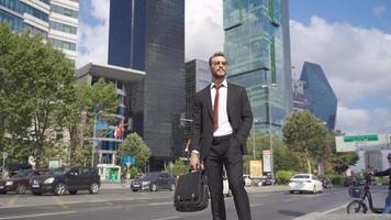 Geschäftsmann Stehen in der Nähe von Büro Gebäude. Geschäftsmann suchen um auf das Straße mit Glas Büro Gebäude im das Hintergrund. video