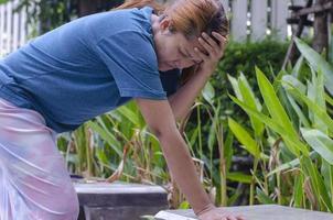 Asian women stand experiencing dizzy or fainting in park because of hot weather photo