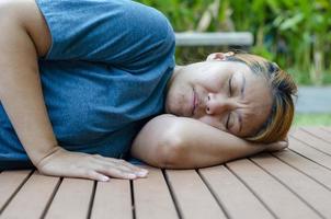 Asian woman lying on her side fainting in the park because of the hot weather photo