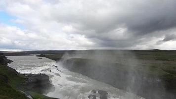 fantastica cascata nel paesaggio dell'Islanda con rocce ed erba. video