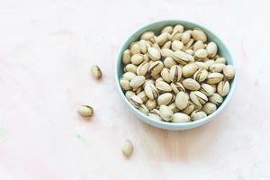 Pistachio in shell in bowl on pink background photo