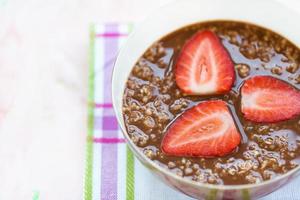 Chocolate oatmeal porridge and strawberry in bowl photo