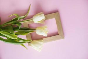 amarillo tulipán flores son arreglado en un rosado antecedentes. el ver desde el arriba, plano poner. vacío espacio para el texto. primavera concepto. De las mujeres día. foto