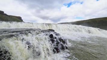 fantastica cascata nel paesaggio dell'Islanda con rocce ed erba. video