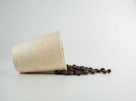 Roasted Arabica coffee beans, ready to make coffee that people like to drink. Placed in a white coffee cup paper on the background. Looks beautiful and appetizing. Drink. photo