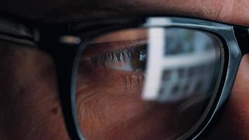 homem dentro óculos olhando em a monitor e surfar Internet. a monitor tela é refletido dentro a óculos video