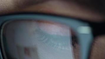 Woman in glasses looking on the monitor and surfing Internet. The monitor screen is reflected in the glasses video
