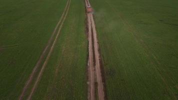 Aerial view of green fields and and a truck driving on a dirt road video