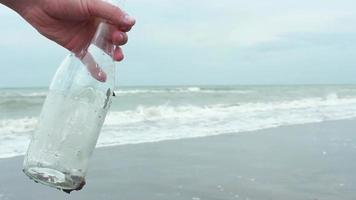 Mann Blätter Brief im Glas Flasche, Verlassen ein Hinweis im ein Glas Flasche und wirft es in Meer, selektiv Fokus video