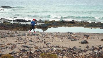 Woman runs along the stony shore of the ocean. Healthy active lifestyle video