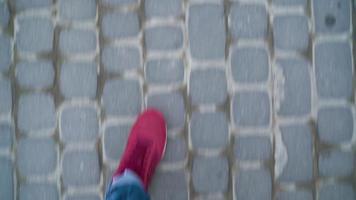 Top view of mens legs in red sneakers walking along the sidewalk video