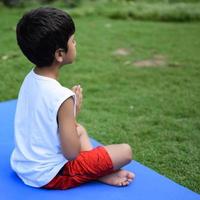 Asian smart kid doing yoga pose in the society park outdoor, Children's yoga pose. The little boy doing Yoga exercise. photo