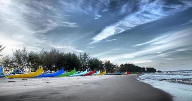 maravilloso ver de serdang playa con filas de vistoso pescar barco en el tarde en belitung isla, Indonesia. foto