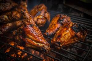 Tasty chicken legs and wings on the grill with fire flames. Neural network photo