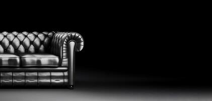 Chesterfield sofa made of black leather on a dark background, isolate. . photo