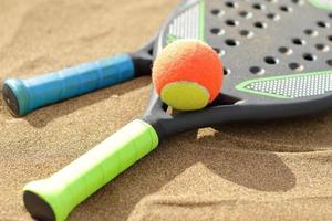 Beach tennis rackets and ball on sand photo