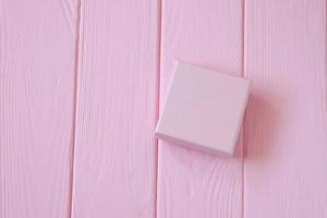 Pink present box on pink wooden background, mockup photo