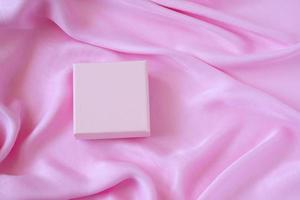 Pink present box on pink silk background, mockup photo