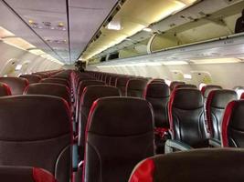 Empty comfortable black and red seats with seatbelts in modern aircraft cabin during flight at daytime photo