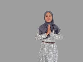 Portrait of a young beautiful Asian Muslim woman wearing a hijab gesturing Eid Mubarak greeting photo