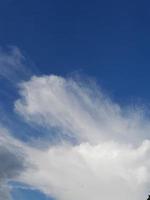 White clouds in the blue sky. Beautiful bright blue background. Light cloudy, good weather. Curly clouds on a sunny day. photo