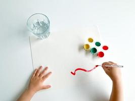 small child draws with paints and brush on white table. fathers day photo