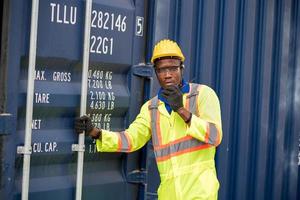 Worker man in protective safety jumpsuit uniform with yellow hardhat and use  Walkie Talkie check container at cargo shipping warehouse. transportation import,export logistic industrial service photo