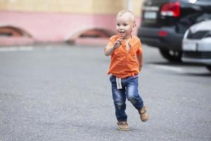 A little boy runs along the road. A child plays in the city. photo