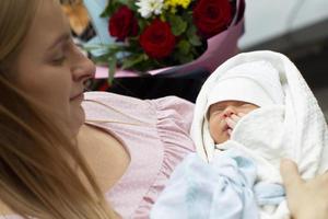 un joven madre sostiene un recién nacido bebé en su brazos en un maternidad hospital. foto