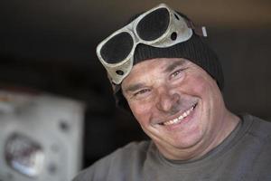 Portrait of a male worker in welding goggles with a dirty face. Auto Mechanic. photo