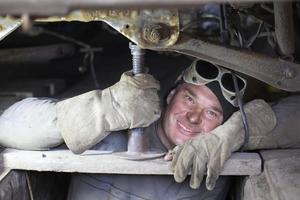 A male auto mechanic repairs a car in a garage.A man repairs a car body. photo