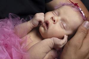 Newborn smart girl sleeps sweetly in her arms. photo