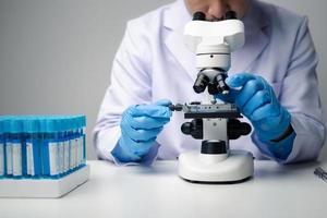 Professional scientist using microscope while working on medical research in science laboratory. photo