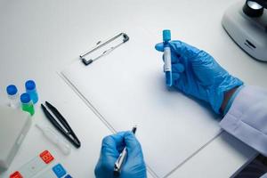 Close up view of scientist researcher taking note while testing substances in laboratory. photo