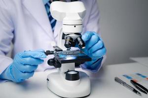 Professional scientist using microscope while working on medical research in science laboratory. photo