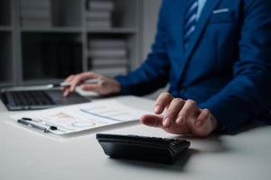 Close up businessman hand using calculator and working with laptop calculate about finance accounting. photo